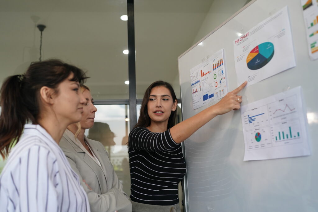 businesswoman pointing at charts on whiteboard during corporate meeting indoor